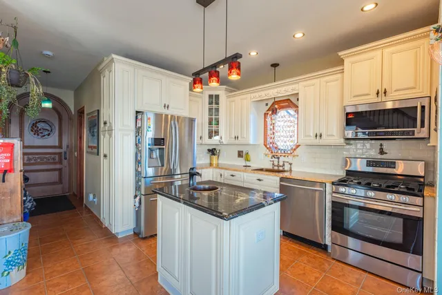 a kitchen with stainless steel appliances granite countertop a stove top oven a sink dishwasher a refrigerator and a dining table with wooden floor