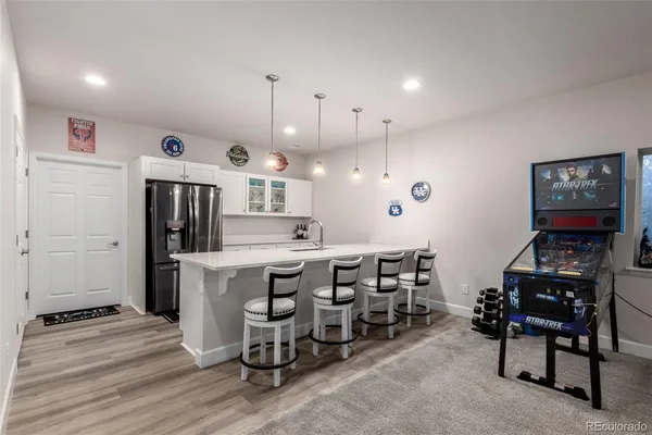 a kitchen with stainless steel appliances kitchen island granite countertop a refrigerator a stove a dining table and chairs with wooden floor
