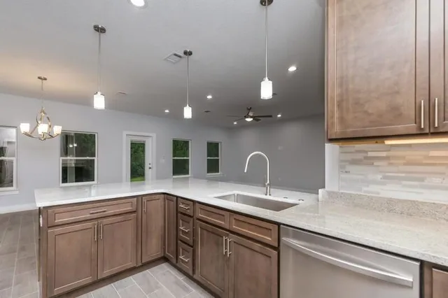 a large kitchen with granite countertop a sink and white cabinets