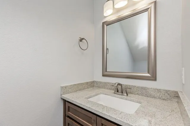 a bathroom with a granite countertop sink and a mirror
