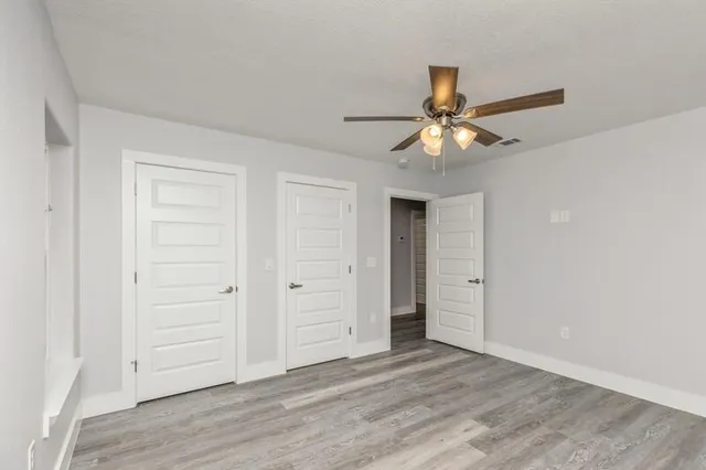 wooden floor in an empty room with a chandelier fan