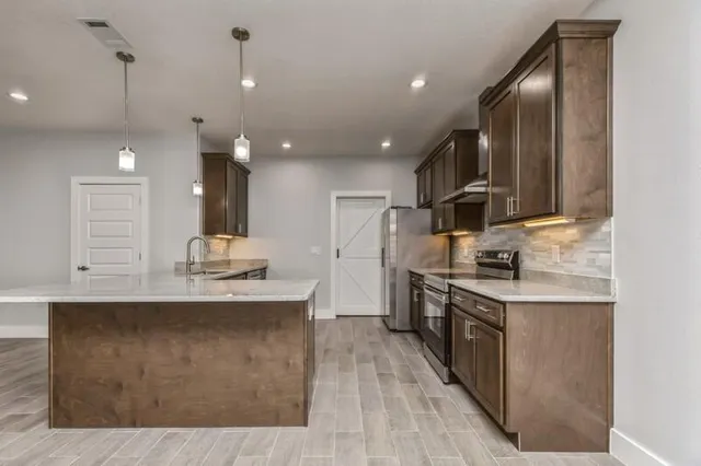 a kitchen with stainless steel appliances granite countertop a sink a stove and a wooden floors