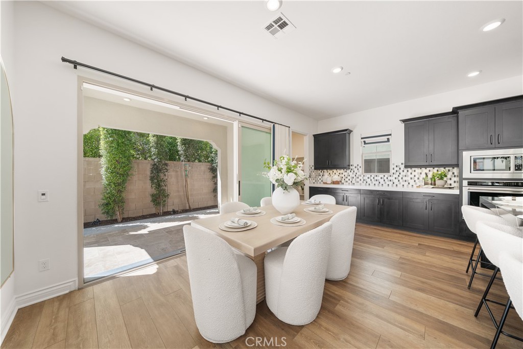 143 Ceremony Irvine, CA 92618 - Photo 20 of 74 a living room with stainless steel appliances a dining table wooden floor and a large window