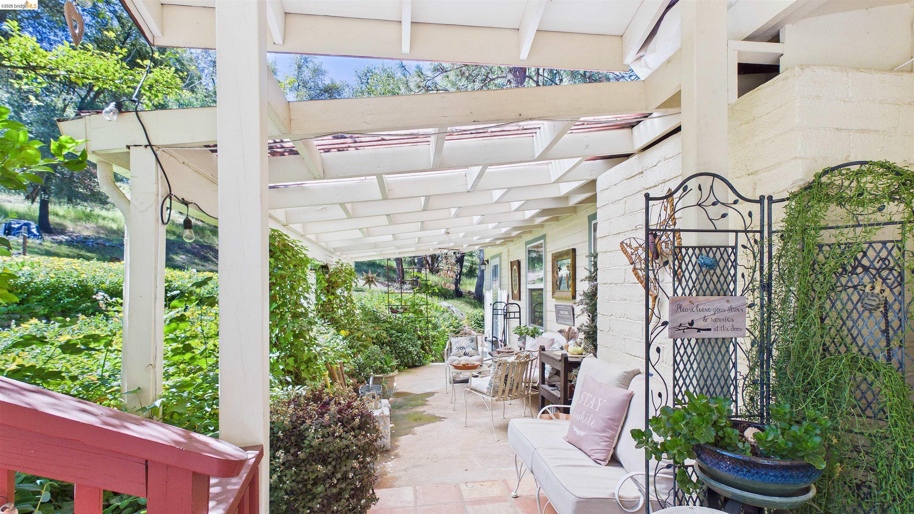 18102 Mt Eaton Road Tuolumne, CA 95379 - Photo 4 of 44 Covered patio featuring an open-beam pergola, light-toned exterior siding, and verdant landscaping