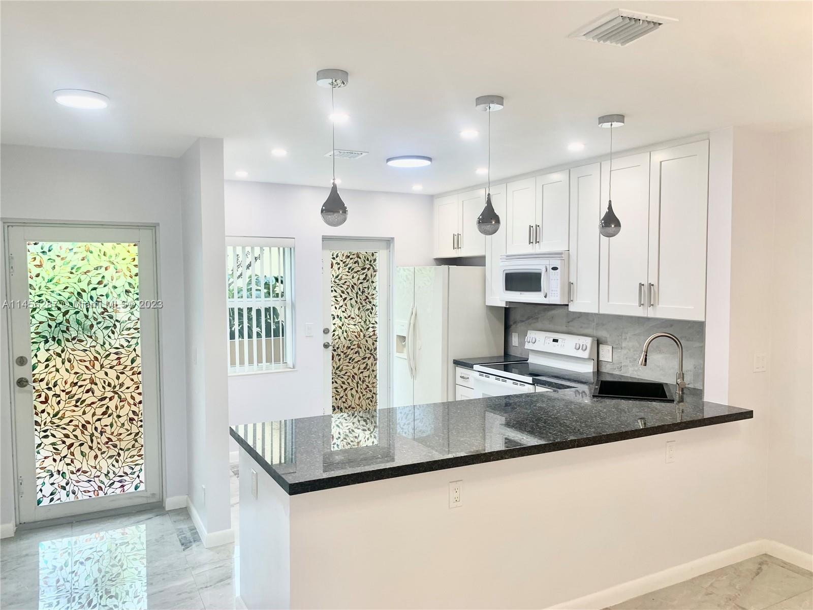 a kitchen with stainless steel appliances granite countertop a granite counter tops and a view of living room