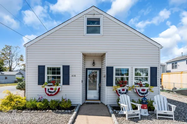 a front view of a house with porch and chairs