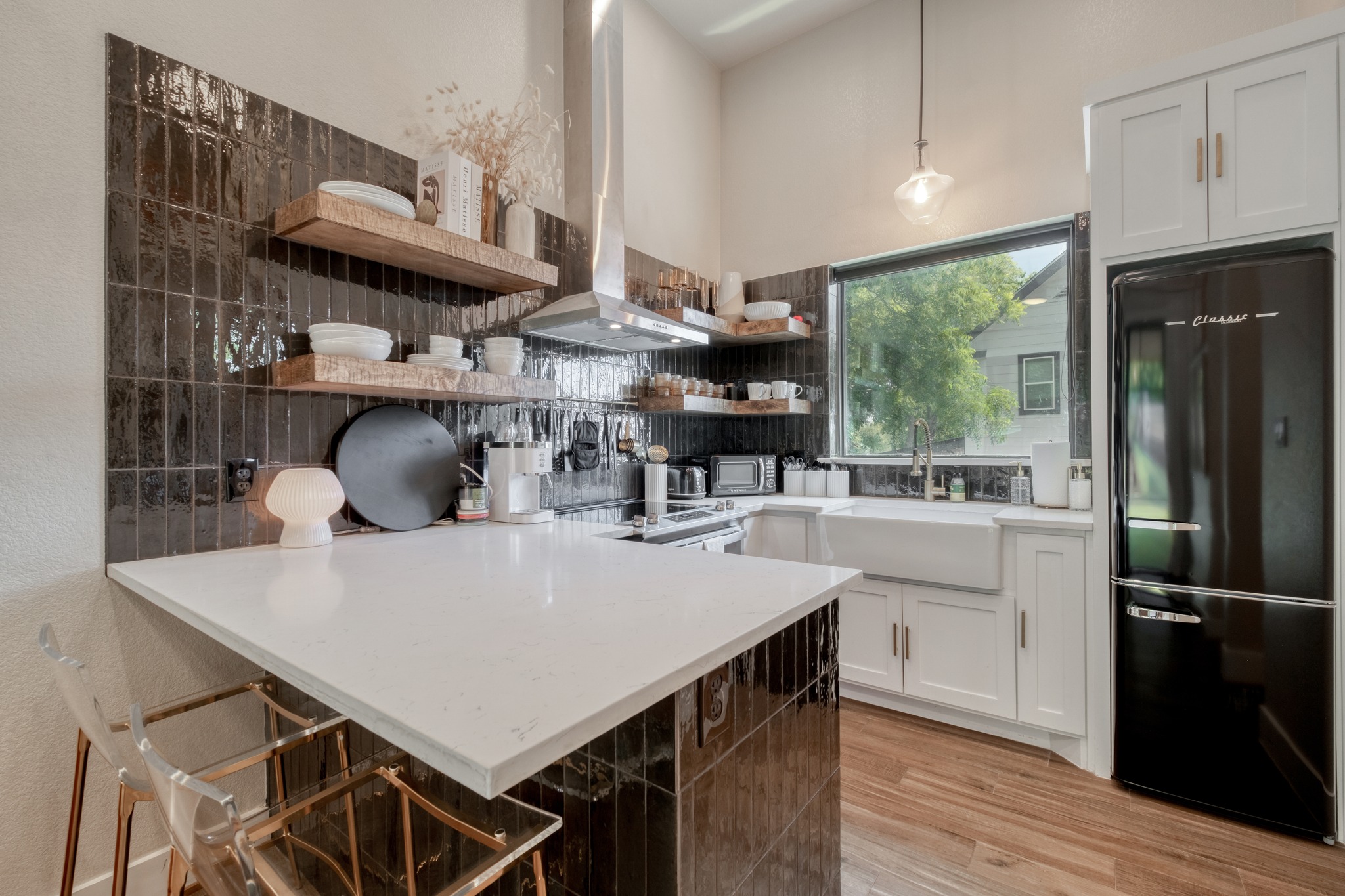1904 East 16th Street, Unit 2 Austin, TX 78702 - Photo 10 of 20 Kitchen featuring dark, vertically-stacked subway tile backsplash, white shaker-style cabinetry, wood-finish flooring, a farmhouse sink, and a black retro-style refrigerator