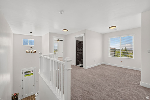 6536 West Muirfield Road Highland, UT 84003 - Photo 14 of 48 Upper-level landing area featuring neutral carpeting, white balusters, and a contemporary chandelier