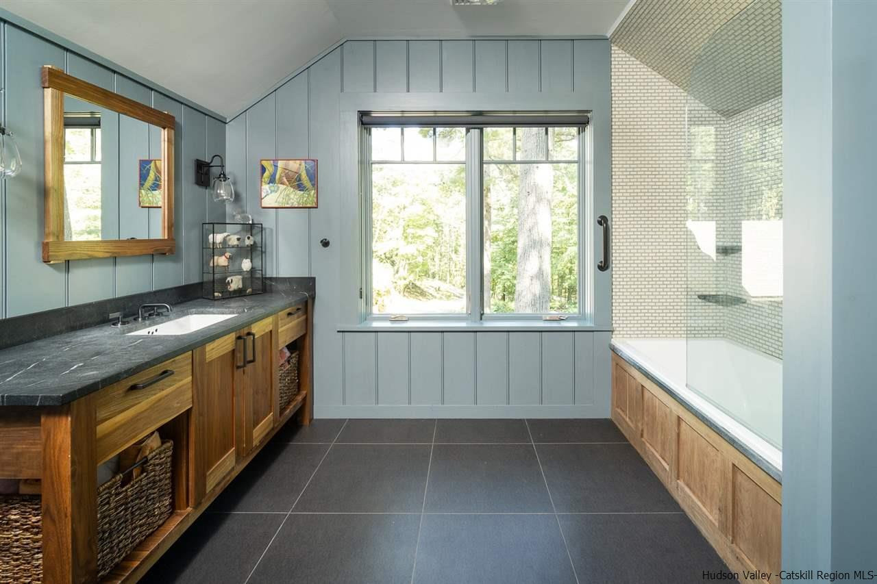 45 Pratt Road Stone Ridge, NY 12484 - Photo 35 of 35 a bathroom with a granite countertop sink a large mirror and a bathtub next to a window