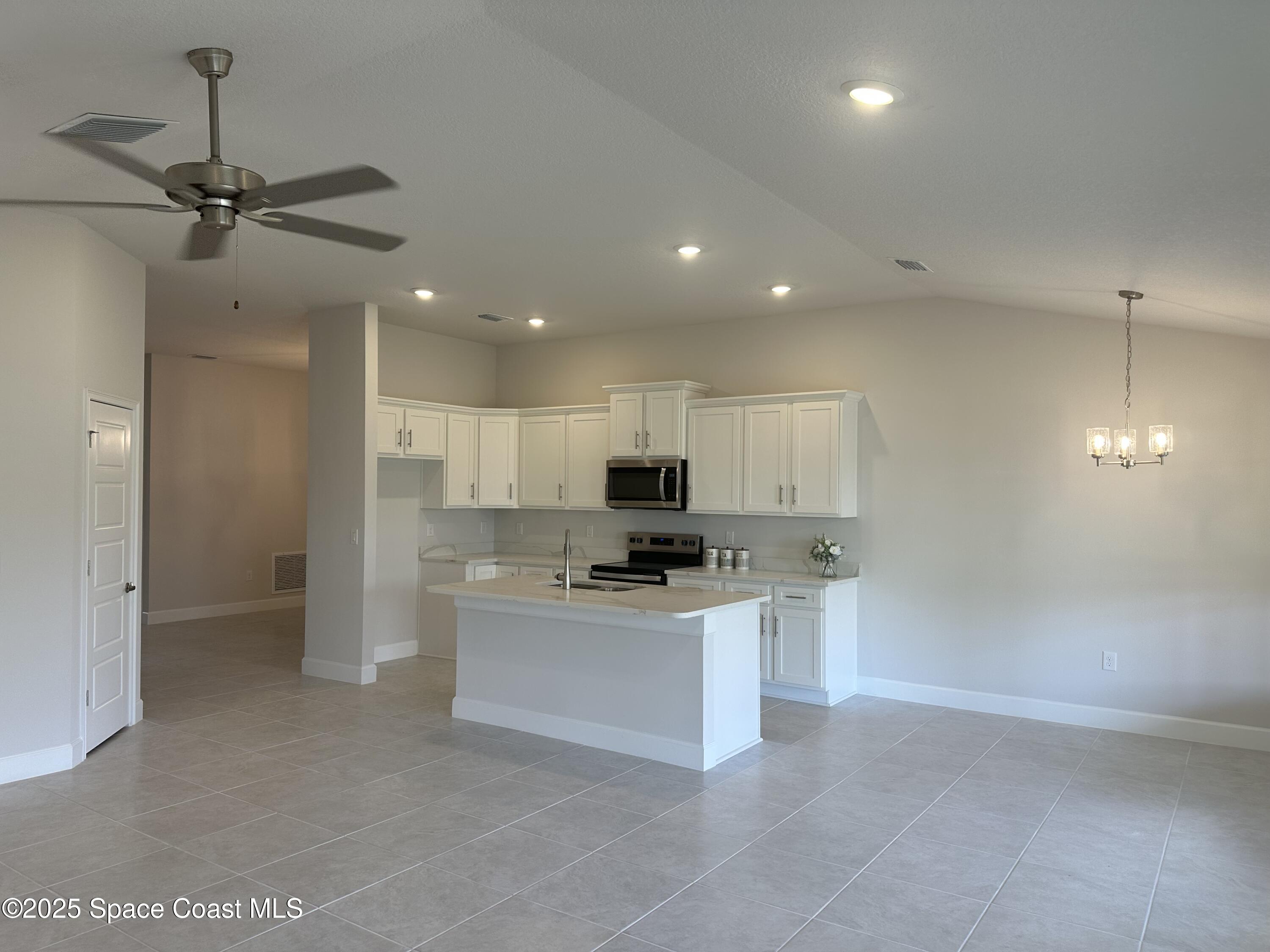 915 Kylar Drive Palm Bay, FL 32907 - Photo 5 of 15 a kitchen with kitchen island a sink stainless steel appliances and white cabinets