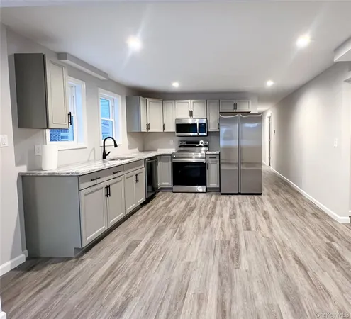 a kitchen with stainless steel appliances kitchen island granite countertop a sink cabinets and wooden floor
