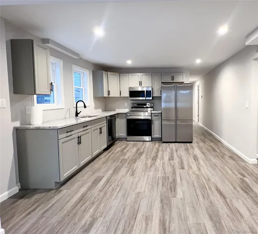 a kitchen with stainless steel appliances kitchen island granite countertop a sink cabinets and wooden floor