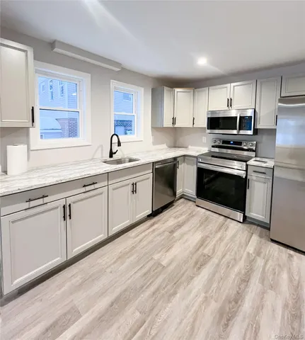 a kitchen with stainless steel appliances granite countertop a stove top oven a sink dishwasher and a microwave oven with white cabinets