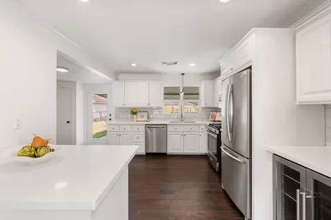 a kitchen with a sink stainless steel appliances and white cabinets