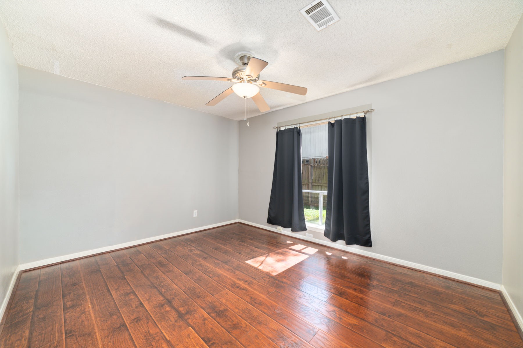 25402 Mill Pond Lane Spring, TX 77373 - Photo 18 of 24 This room features hardwood flooring, a ceiling fan, and a large window with dark curtains, offering natural light and a cozy atmosphere. Great for an office, media room, or bedroom.