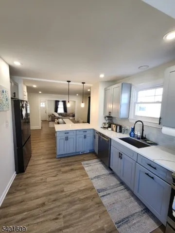 a large kitchen with a large counter top a sink stainless steel appliances and cabinets