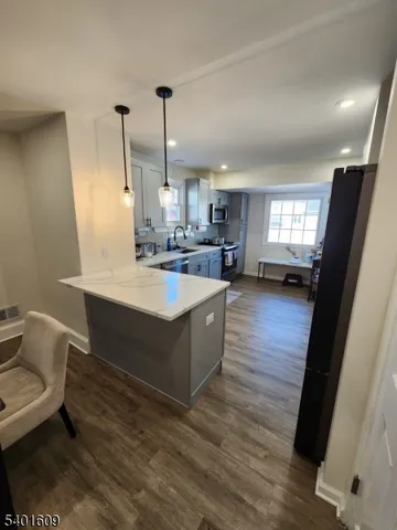 a kitchen with a sink appliances and wooden floor