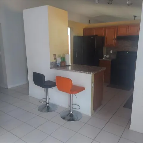 a kitchen with stainless steel appliances kitchen island granite countertop a refrigerator and a sink