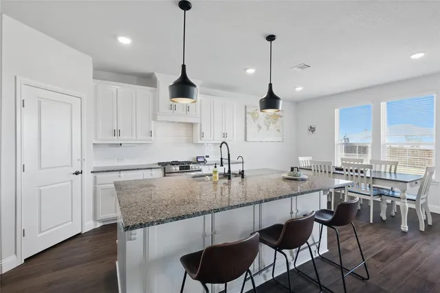 a kitchen with granite countertop a dining table chairs sink and cabinets