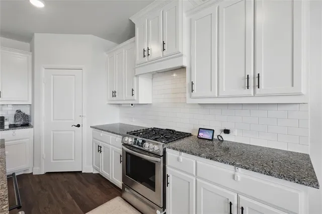 a kitchen with granite countertop white cabinets and stainless steel appliances
