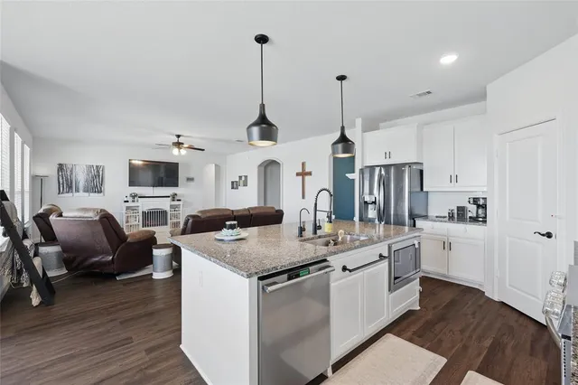 a open kitchen with stainless steel appliances granite countertop a stove and white cabinets with wooden floor
