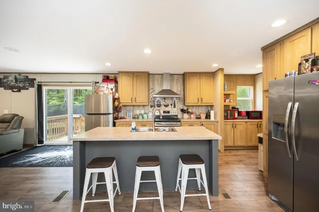 a kitchen with stainless steel appliances granite countertop a table chairs refrigerator and sink