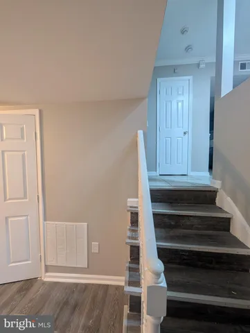a view of a hallway with wooden floor and a bathroom