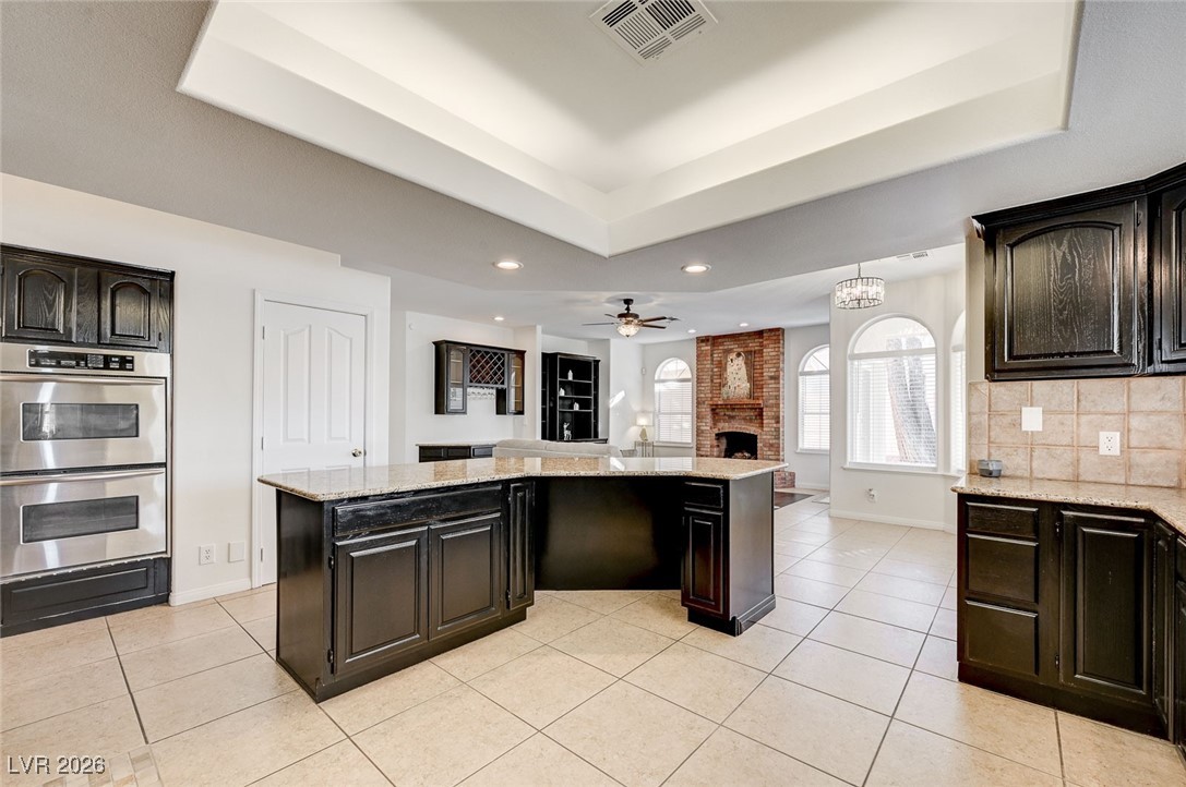2955 El Camino Road Las Vegas, NV 89146 - Photo 28 of 99 Kitchen featuring a center island, double oven, dark brown cabinets, and a fireplace