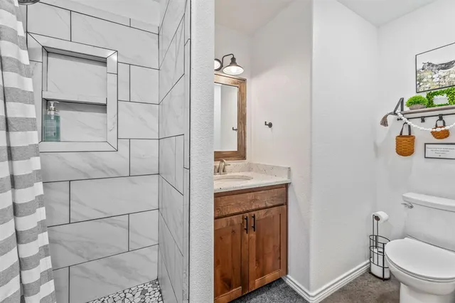 a bathroom with a granite countertop sink a toilet and mirror