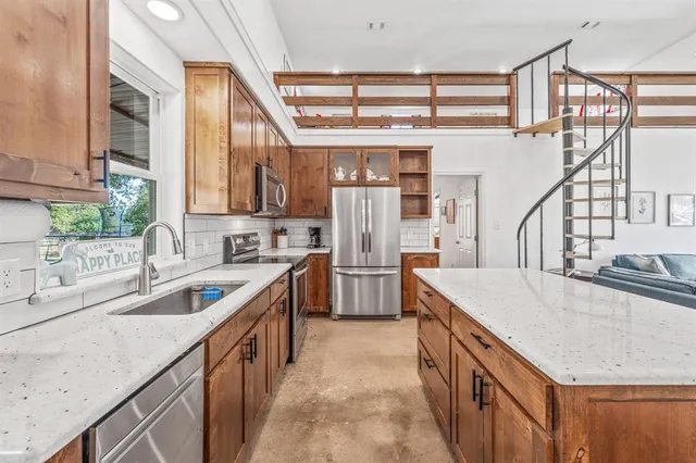 a kitchen with stainless steel appliances granite countertop a sink and a refrigerator
