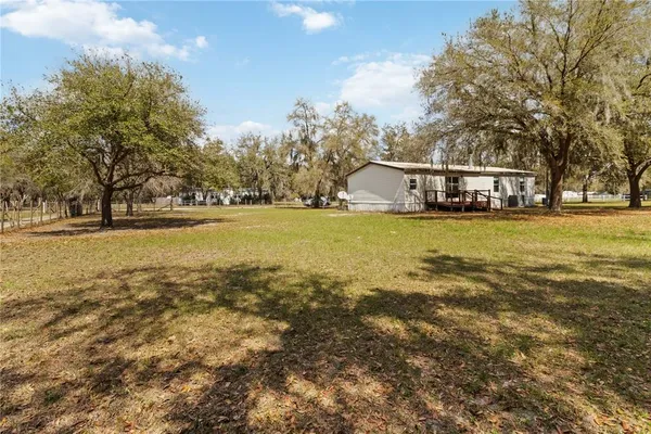 a view of a house with a big yard and large trees