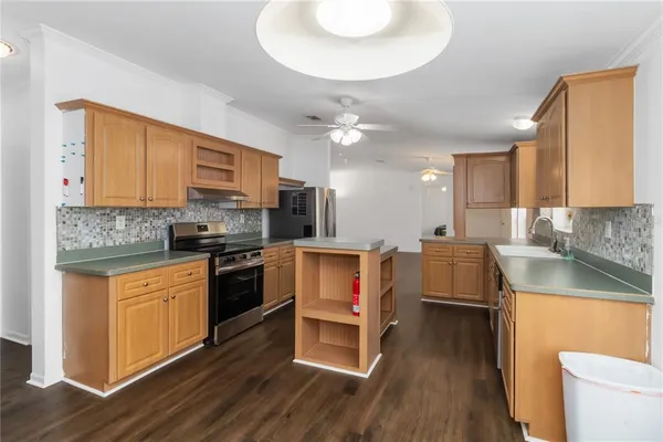 a kitchen with stainless steel appliances a stove a sink dishwasher a refrigerator white cabinets and wooden floor