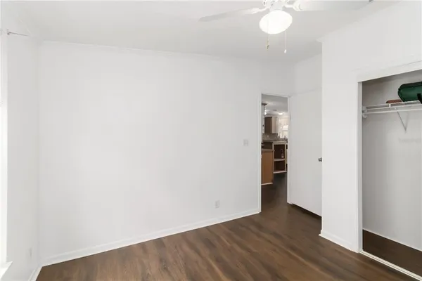 a view of an empty room with wooden floor and cabinets