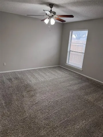 an empty room with windows and fan chandelier fan