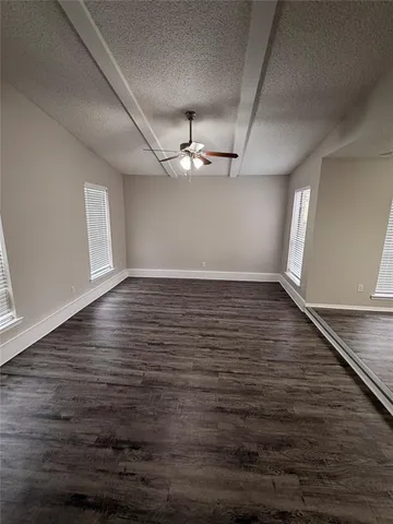 an empty room with wooden floor chandelier fan and windows