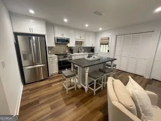 a kitchen with stainless steel appliances granite countertop a refrigerator a stove a sink dishwasher and a oven with wooden floor