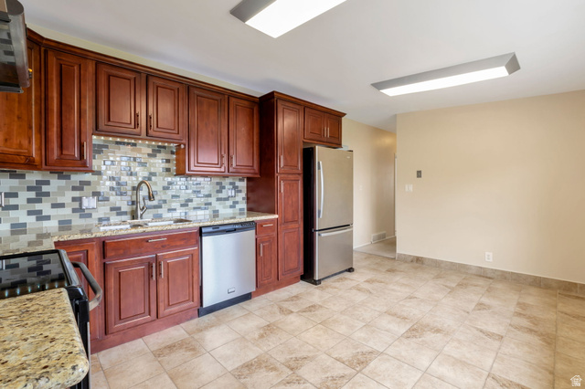 447 550 South Bountiful, UT 84010 - Photo 5 of 25 Kitchen featuring dark wood cabinetry, stainless steel appliances, granite countertops, and a mosaic tile backsplash