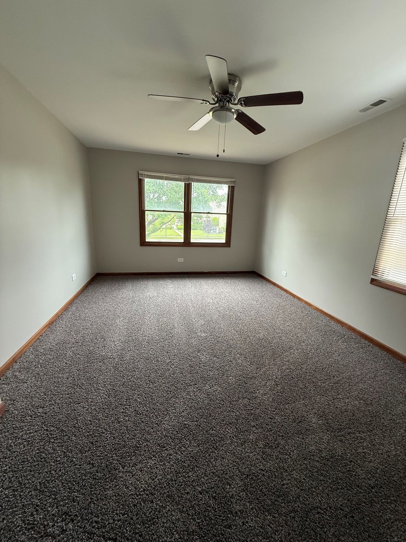 674 East Algonquin Road Des Plaines, IL 60016 - Photo 15 of 19 an empty room with a chandelier fan and windows