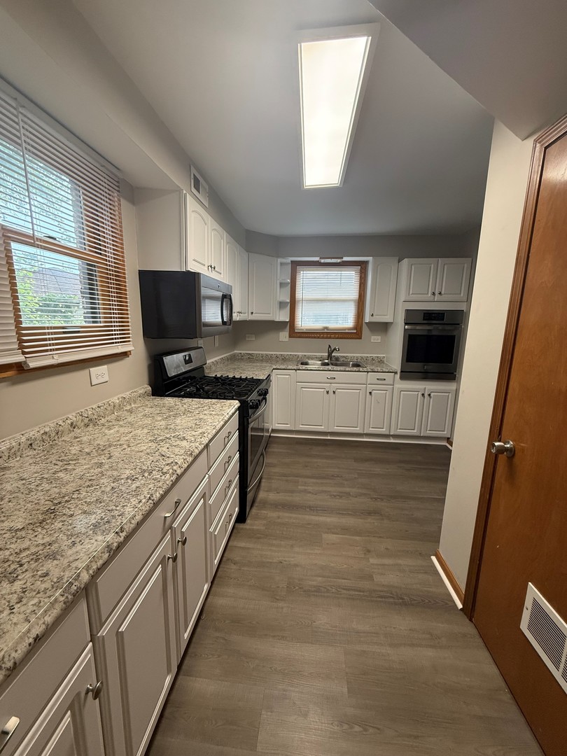 674 East Algonquin Road Des Plaines, IL 60016 - Photo 6 of 19 a large kitchen with a stove a sink dishwasher and a microwave oven with wooden floor