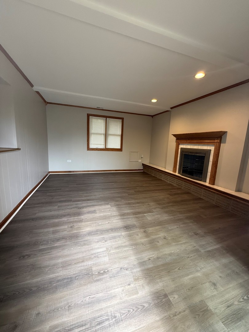674 East Algonquin Road Des Plaines, IL 60016 - Photo 10 of 19 an empty room with wooden floor and fireplace