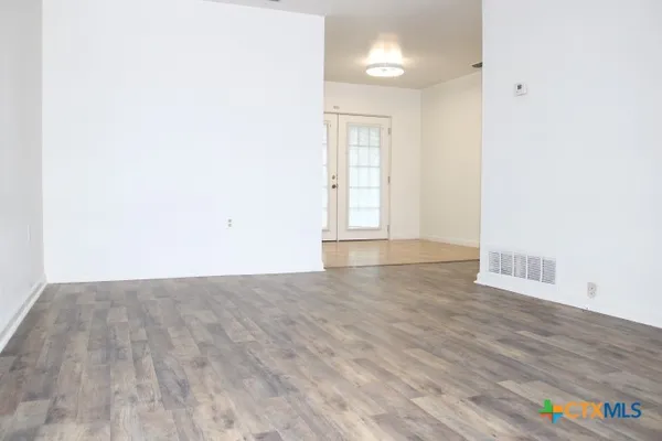 an empty room with wooden floor and windows