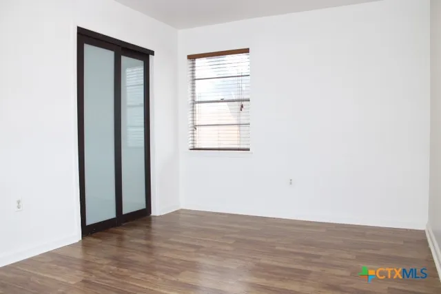 an empty room with wooden floor and windows