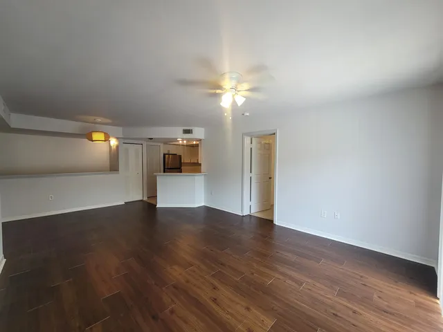 a view of a hallway with wooden floor and a kitchen