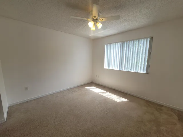 an empty room with windows and chandelier fan