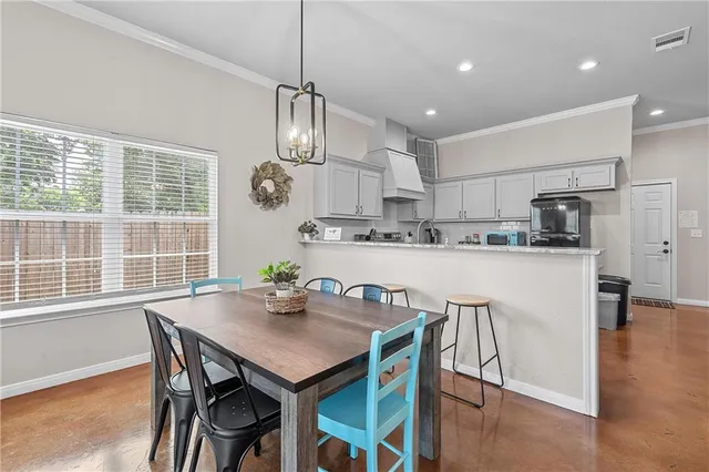 a kitchen with stainless steel appliances kitchen island granite countertop a dining table chairs and white cabinets