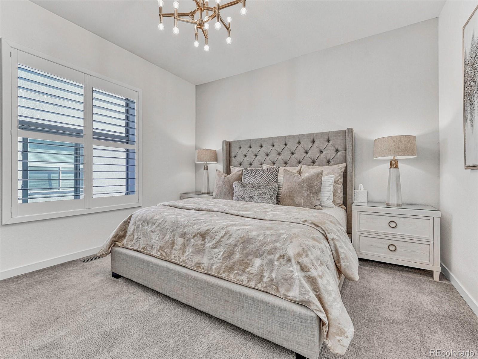 10132 Belvedere Loop Lone Tree, CO 80124 - Photo 12 of 37 a bedroom with a bed and a chandelier