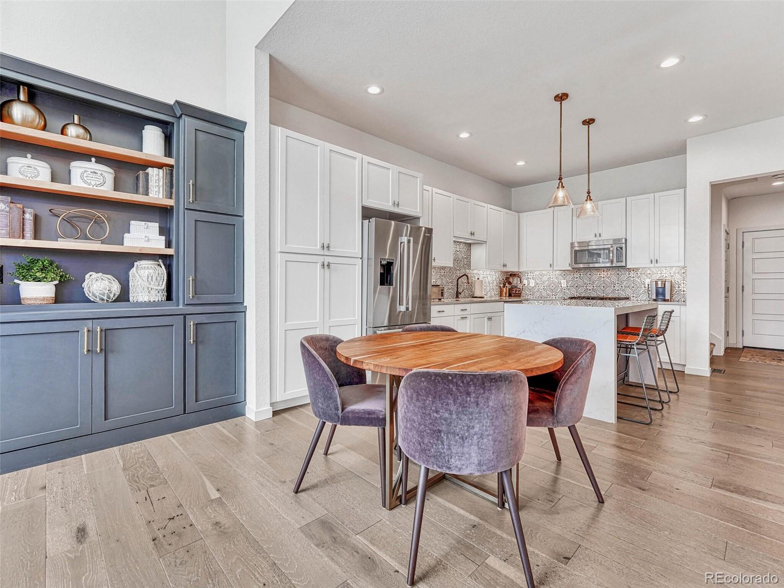 10132 Belvedere Loop Lone Tree, CO 80124 - Photo 6 of 37 a kitchen with stainless steel appliances kitchen island granite countertop a dining table chairs sink and cabinets
