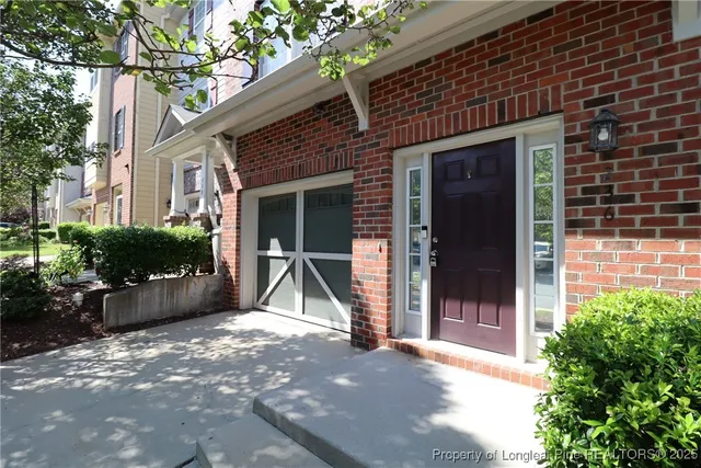 a view of yellow house with potted plants in front of door