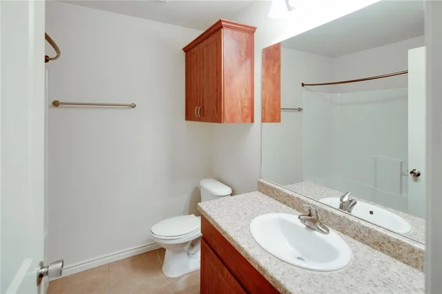 a bathroom with a toilet sink vanity granite and shower