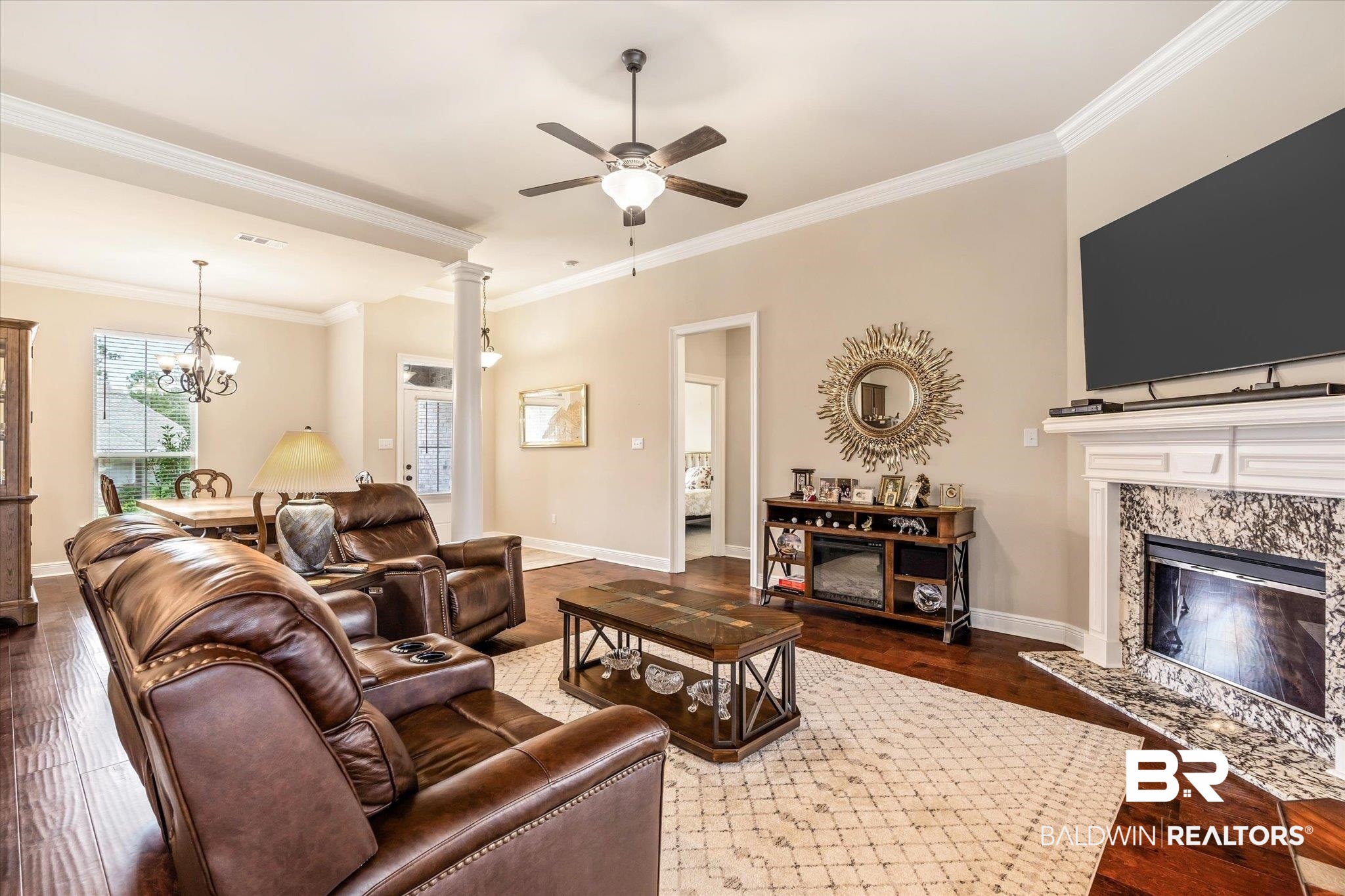 1786 Vivace Drive Foley, AL 36535 - Photo 7 of 21 Living area featuring dark wood-style floors, crown molding, a premium fireplace, ceiling fan, and a chandelier